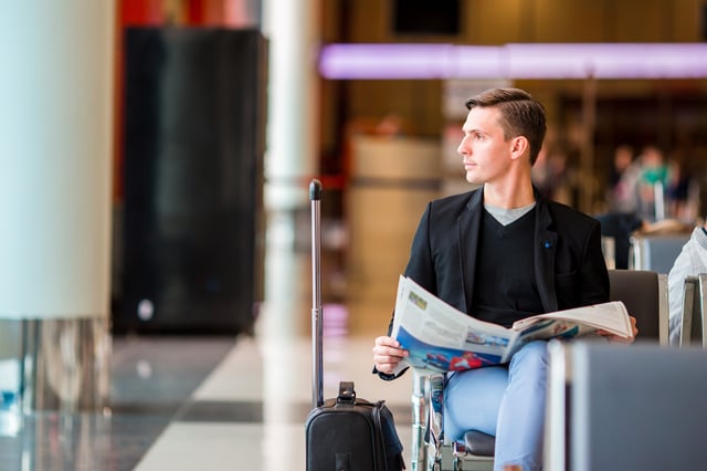 Young man with a laptop at the airport while waiting for his flight