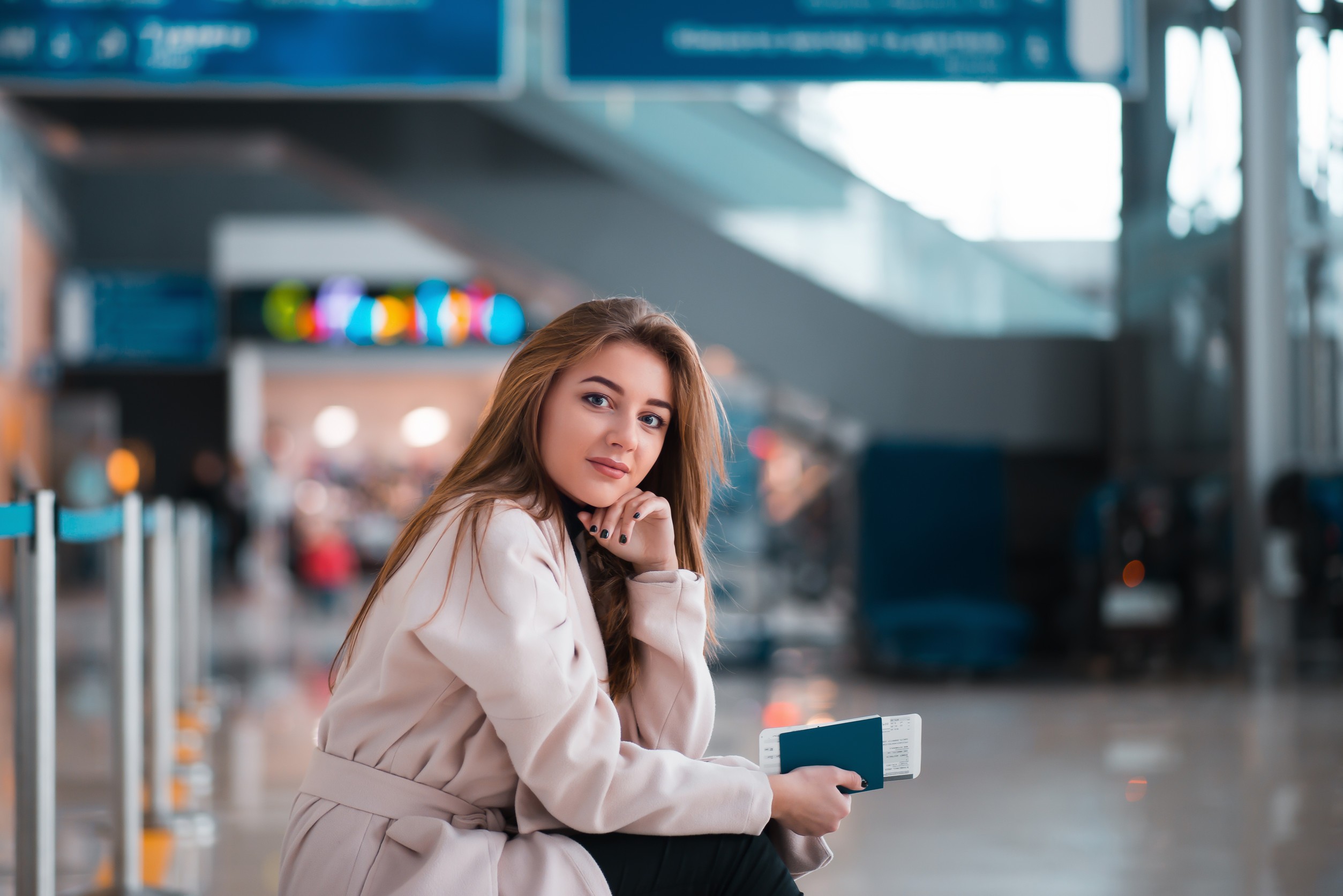 Young Girl Sits on a Suitcase and Holds the Passport and the Ticket in Hand
