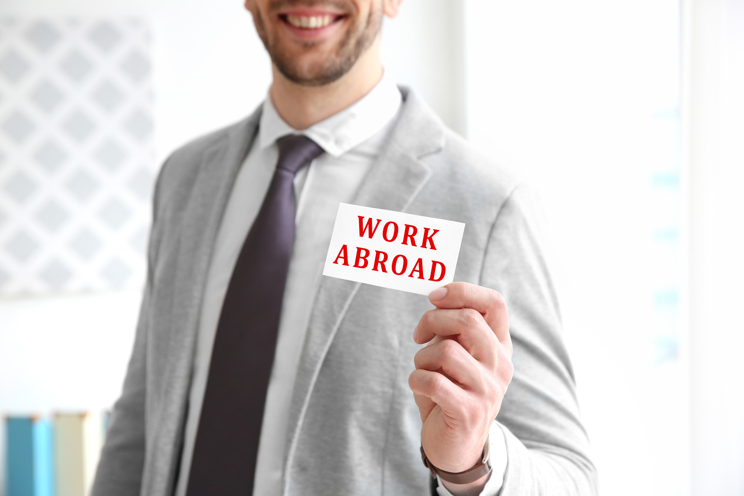 Young man holding business card with text work abroad